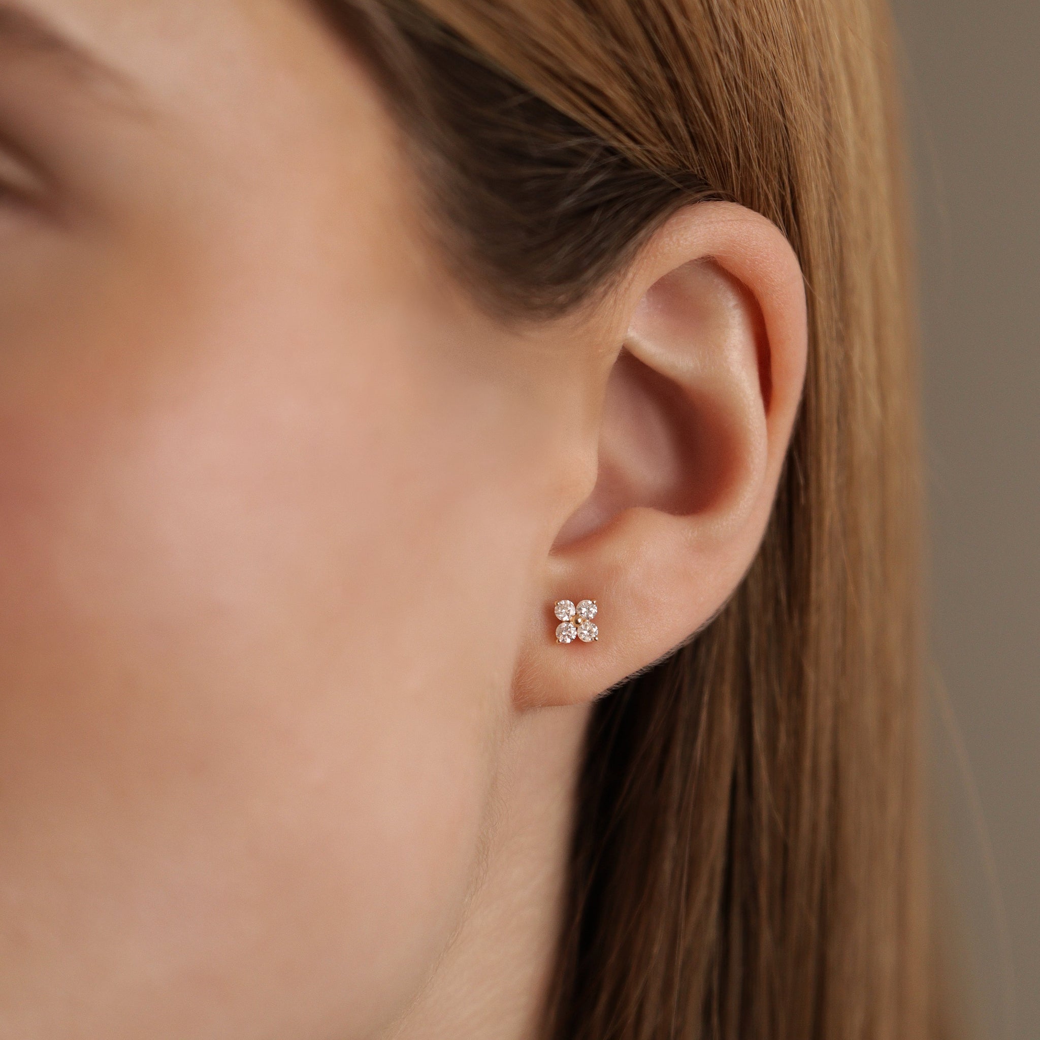 Julie Ohrstecker aus 18k Gold mit vier Brillanten - elegante Blütenform, getragen am Ohr.