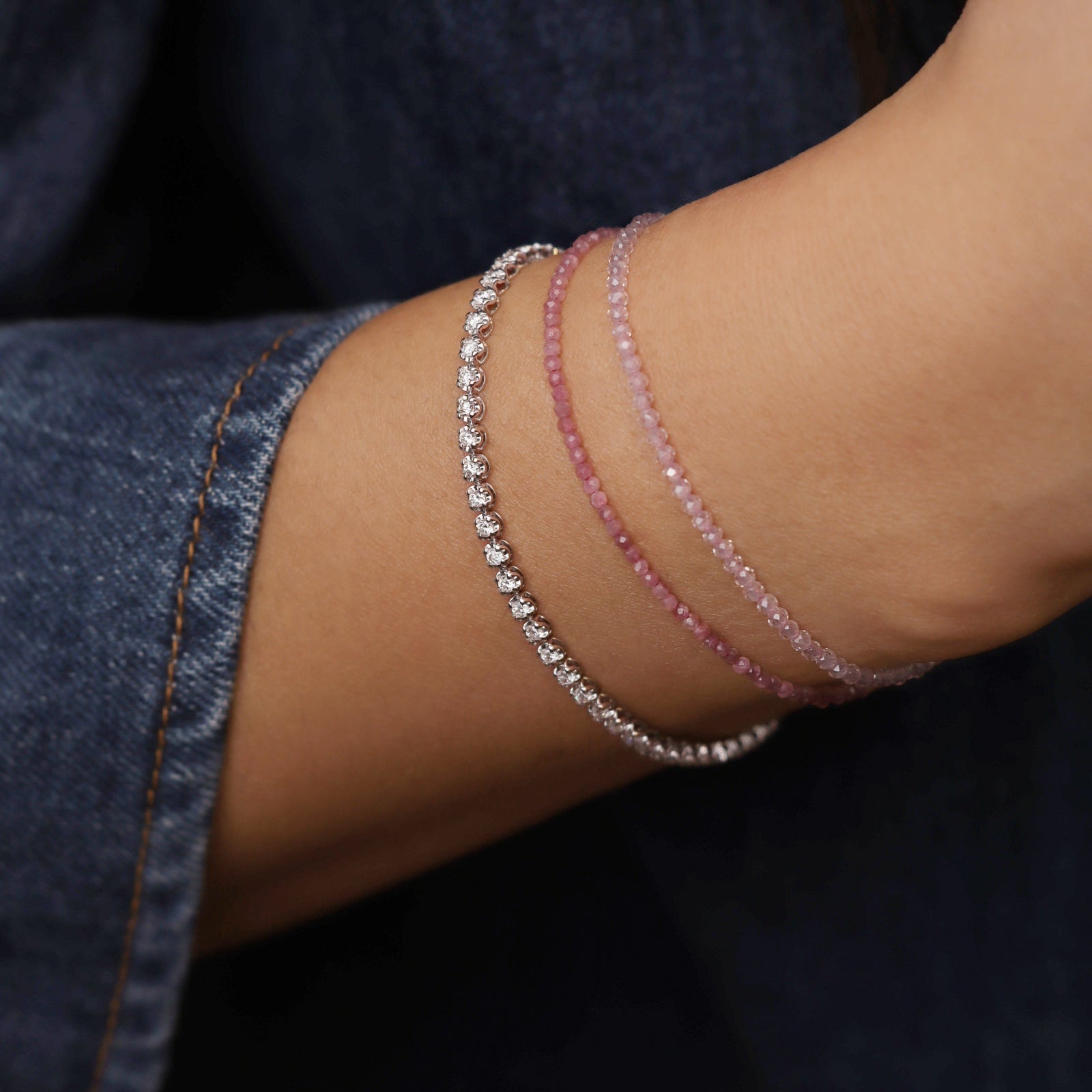 Diamant Tennisarmband aus 18 Karat Gold im eleganten Layering-Look mit feinen Edelsteinarmbändern.