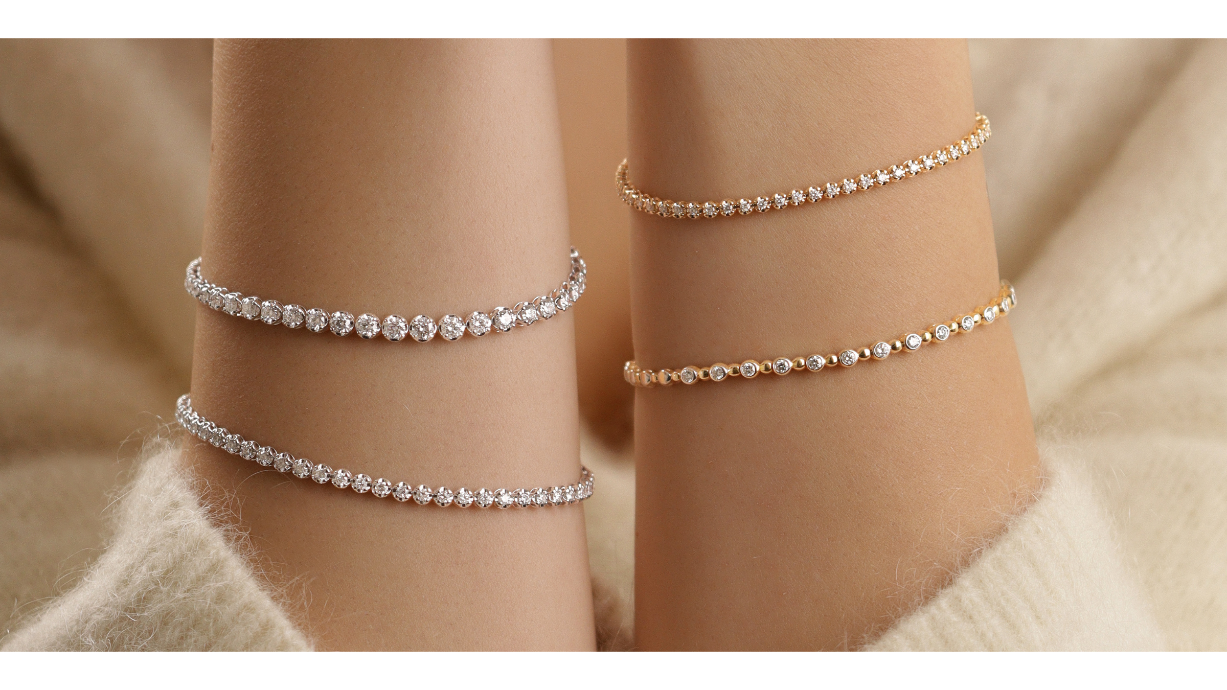 Zwei elegante Handgelenke mit mehreren funkelnden Tennisarmbändern in Weiß- und Gelbgold - fotografiert im warmen, soften Vasana Jewelry-Stil.