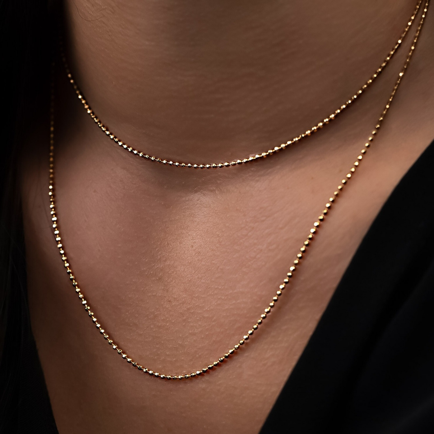 Goldkette aus 18 Karat mit facetierten Kügelchen am Hals getragen - layering möglich.