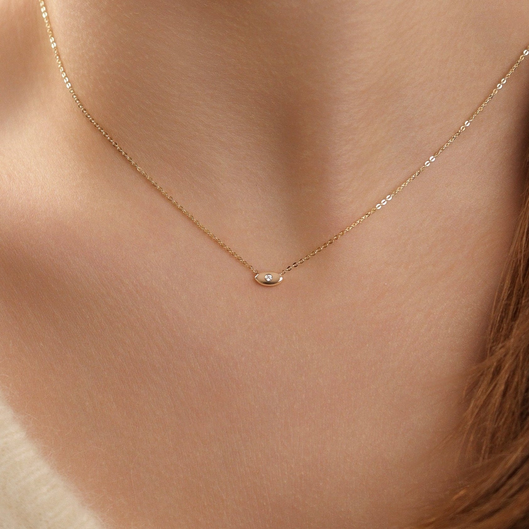 Lucky Eye Halskette in 18 Gelbgold, getragen am Hals - zarte Kette mit Evil-Eye Anhänger und funkelndem Stein. 