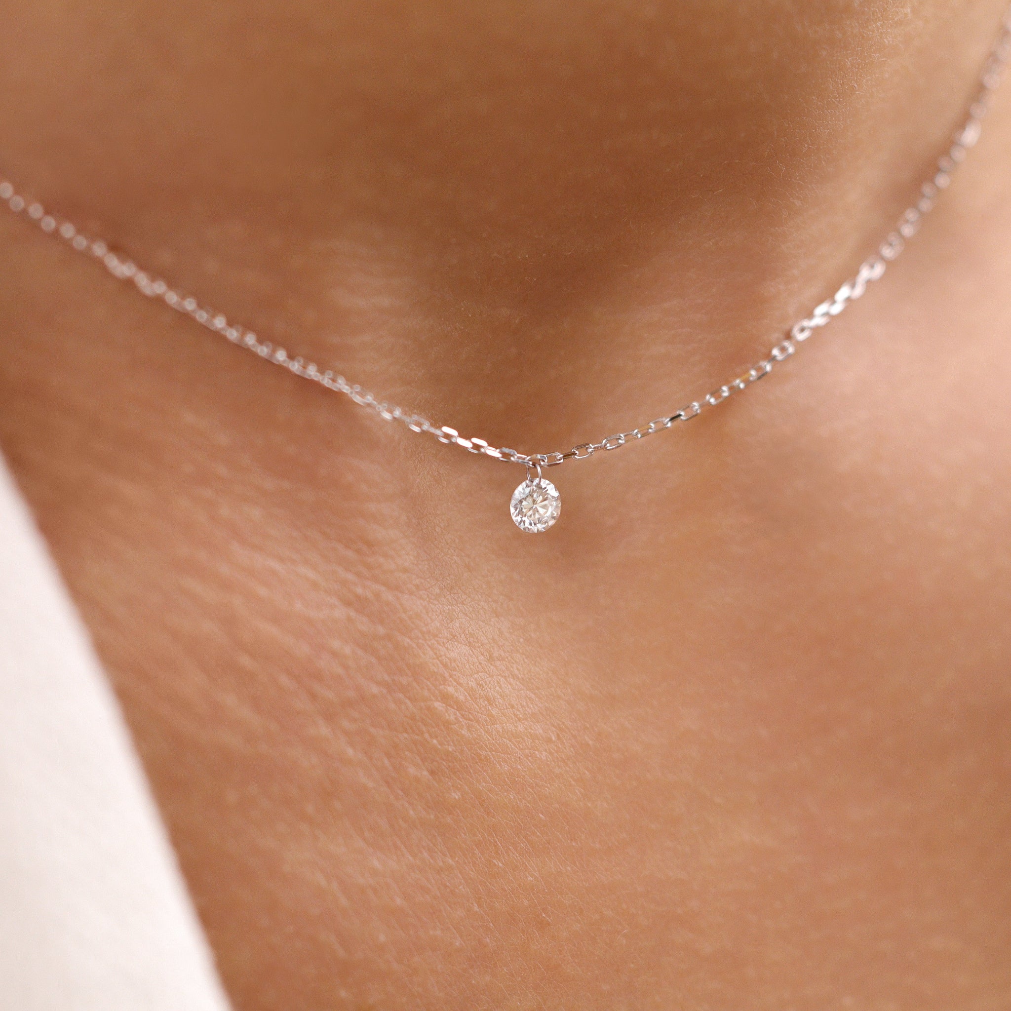 Feine 18K Gold Halskette mit funkelndem Diamantanhänger - elegantes, minimalistisches Schmuckstück von Vasana Jewelry am Dekollete getragen.